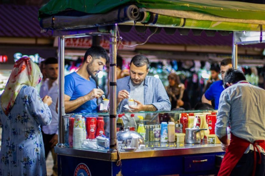 man in white dress shirt standing in front of food stall