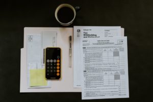 black Android smartphone near ballpoint pen, tax withholding certificate on top of white folder