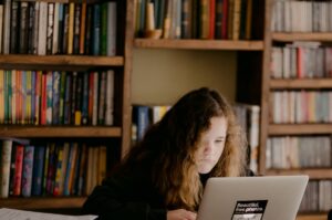 woman in black long sleeve shirt using macbook air on brown wooden table